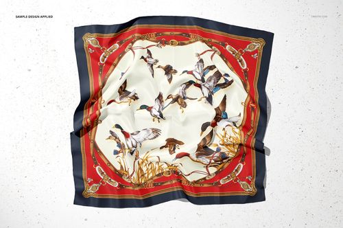 Top view of a silk scarf mockup featuring a colorful bird and ribbon design with red and black edges on a light surface.