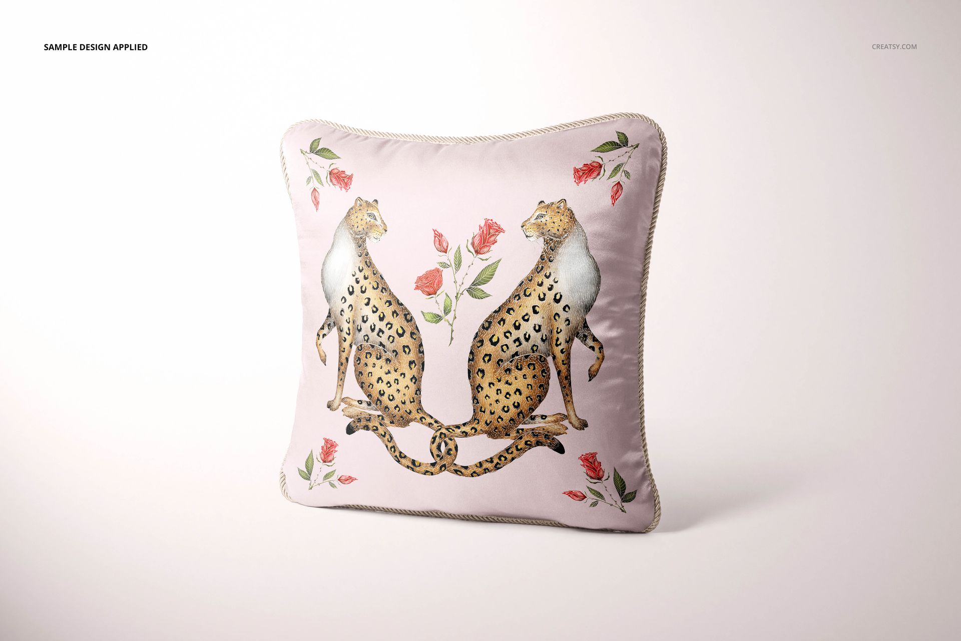 Silk pillow mockup with braided edge, decorated with two leopards and red roses, displayed on a plain backdrop.