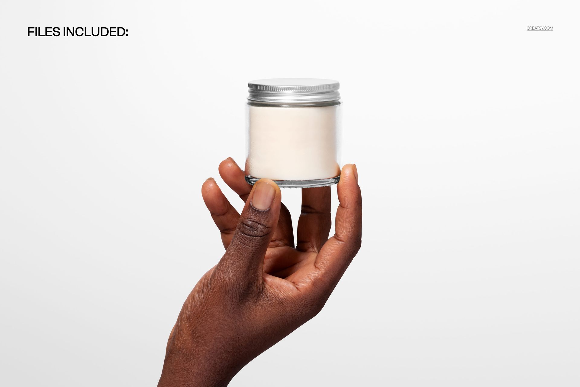 Clear glass candle jar with silver lid held by a hand, shown against a plain white background in a mockup scene.