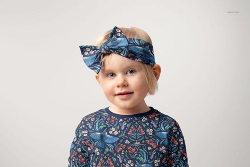 Front view of a child wearing a blue patterned bow tie headband and matching shirt, featured in a PSD mockup.
