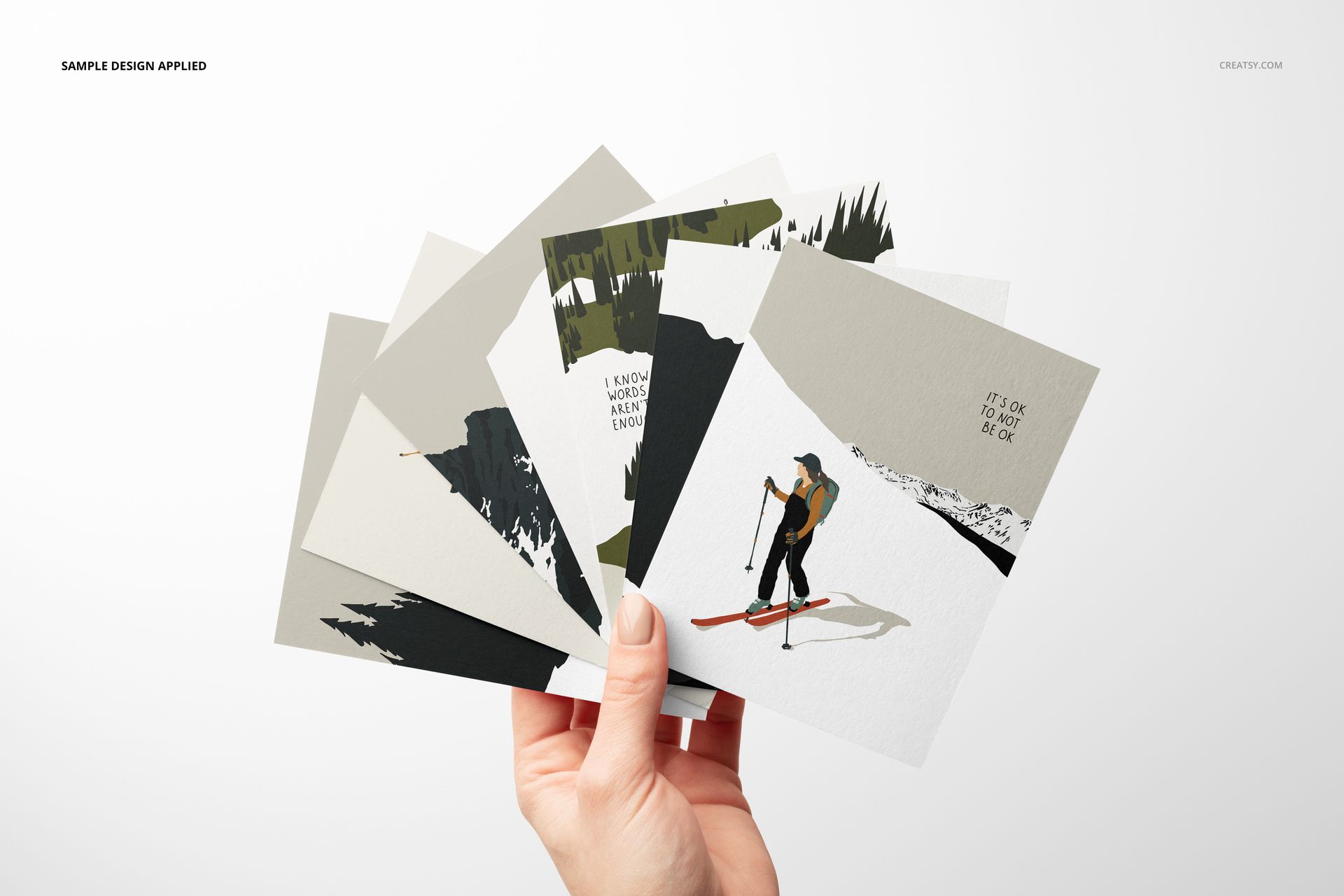 Front view of a hand displaying several A2 cards mockup with nature-themed designs, arranged in a fan shape.