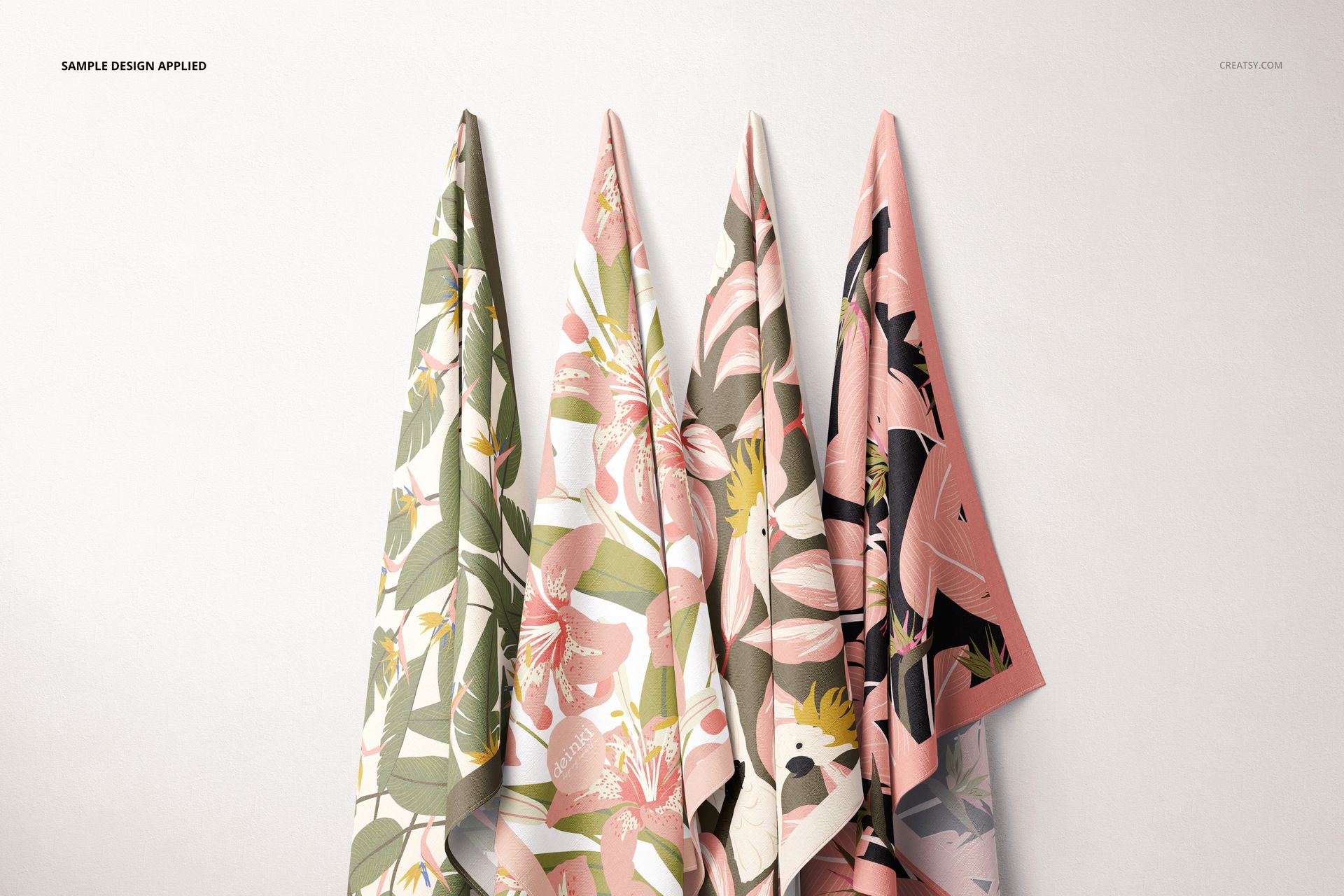 Four hanging fabric pieces with floral and botanical patterns in pink, green, and beige tones, front view against a light wall.