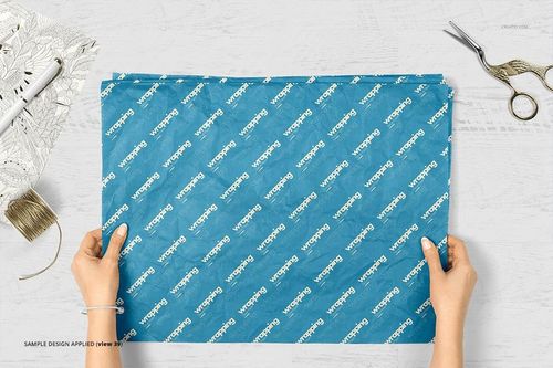 Top view of blue wrapping tissue paper mockup with a geometric pattern, surrounded by scissors and crafting tools.