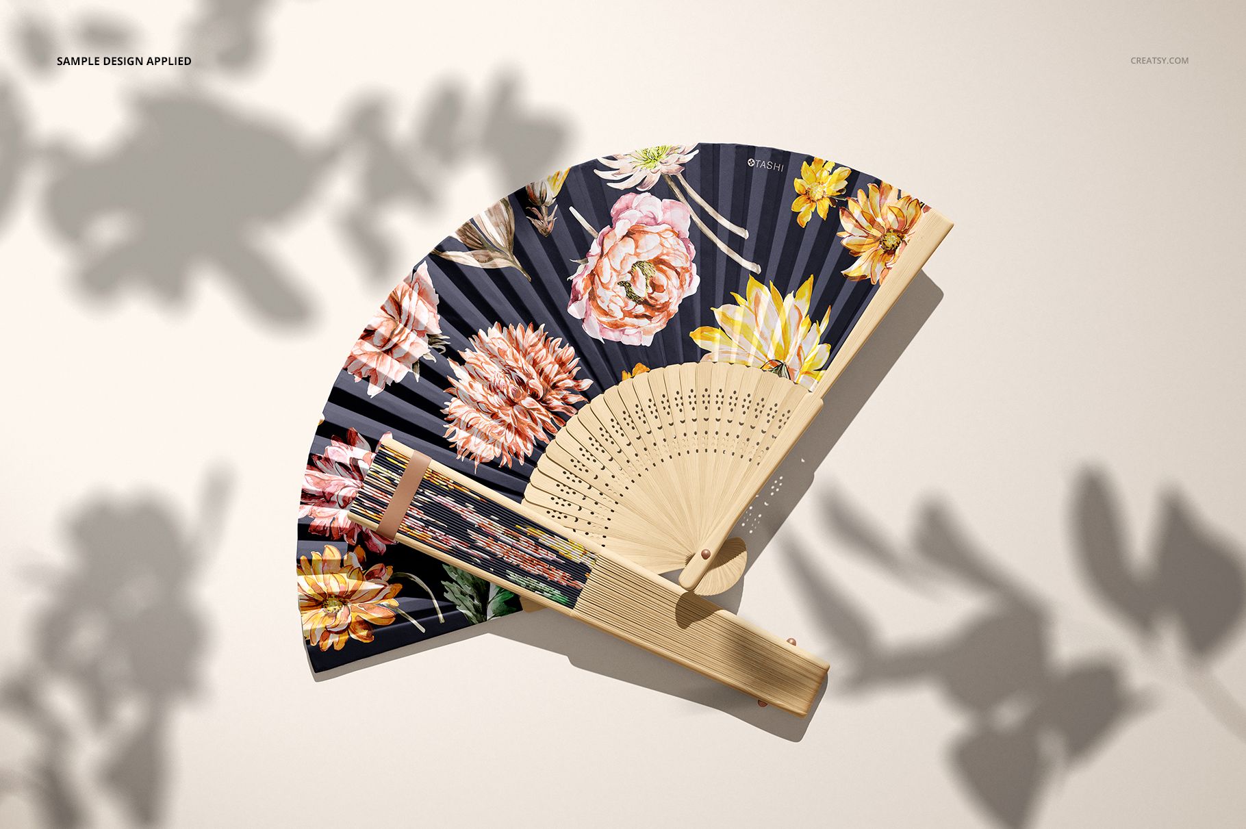 PSD mockup of a fabric hand fan with a wooden frame, shown from above with vibrant flowers on the fan material.