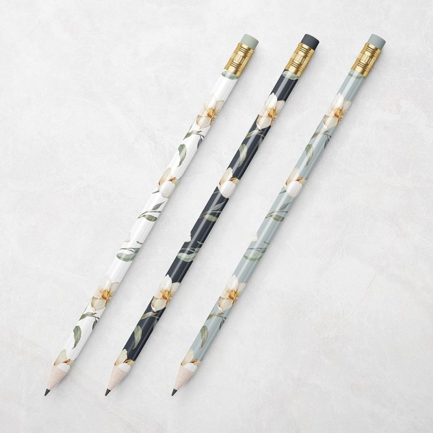 Three pencils with floral patterns in white, black, and gray tones are arranged diagonally on a light textured surface.