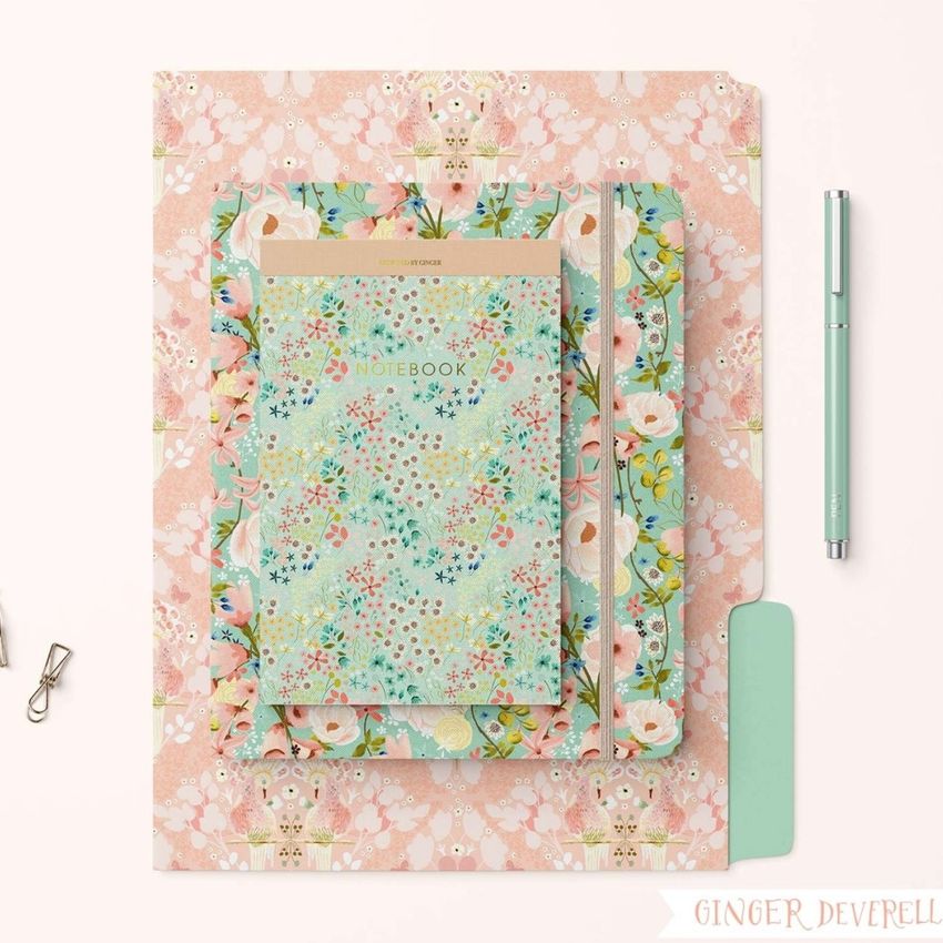 Stationery set mockup featuring a pastel floral notebook, folders, and pen arranged on a light surface with soft shadows.