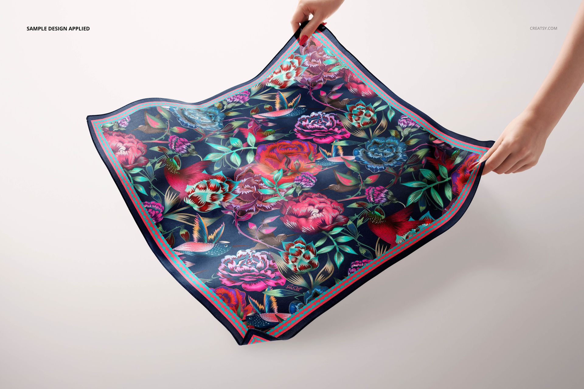 Colorful square silk scarf mockup featuring bold flower designs, shown from a top view with hands holding the corners.