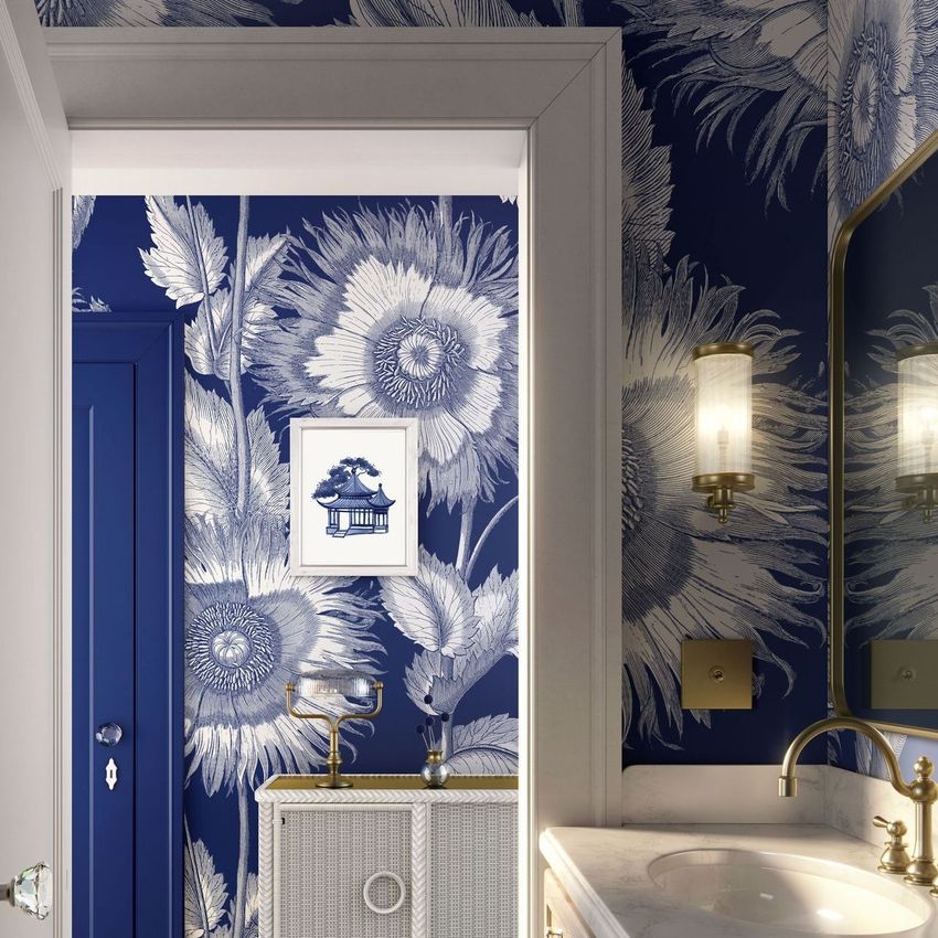 Modern art deco bathroom mockup featuring bold blue and white floral wallpaper, a framed artwork, and a marble sink with gold fixtures.