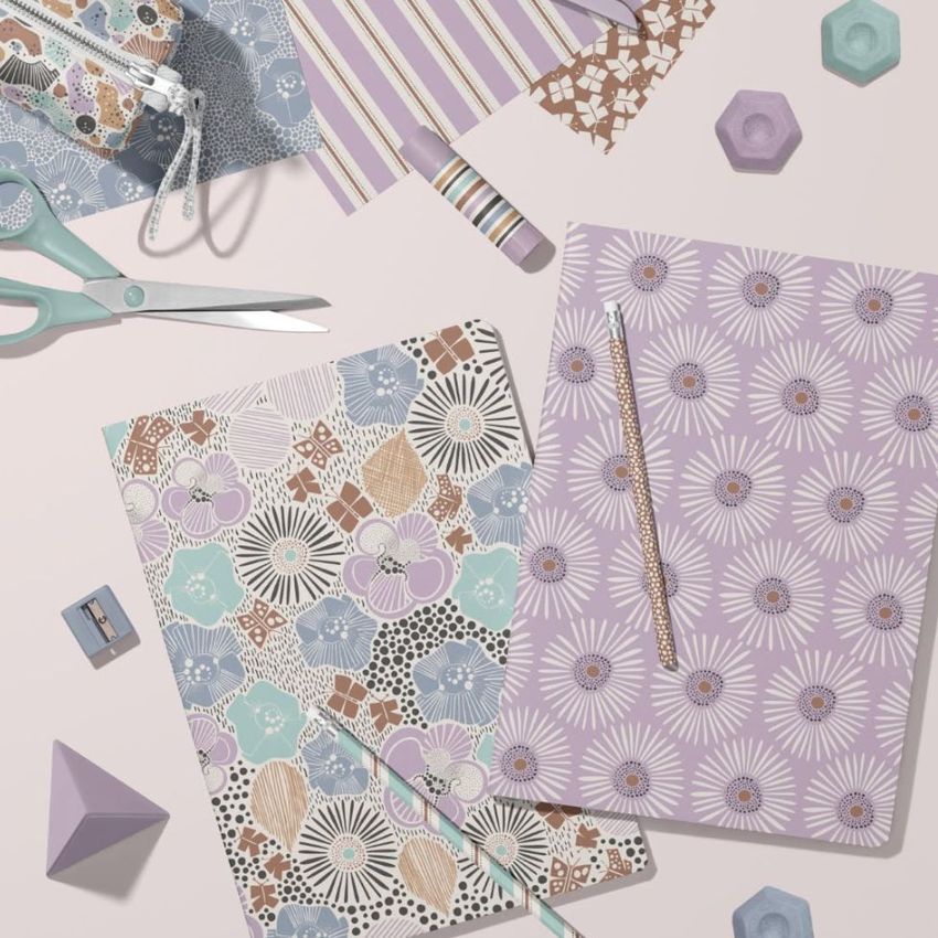 Stationery mockup featuring two A4 notebooks with pastel floral patterns, surrounded by scissors, tape, and geometric props on a light surface.