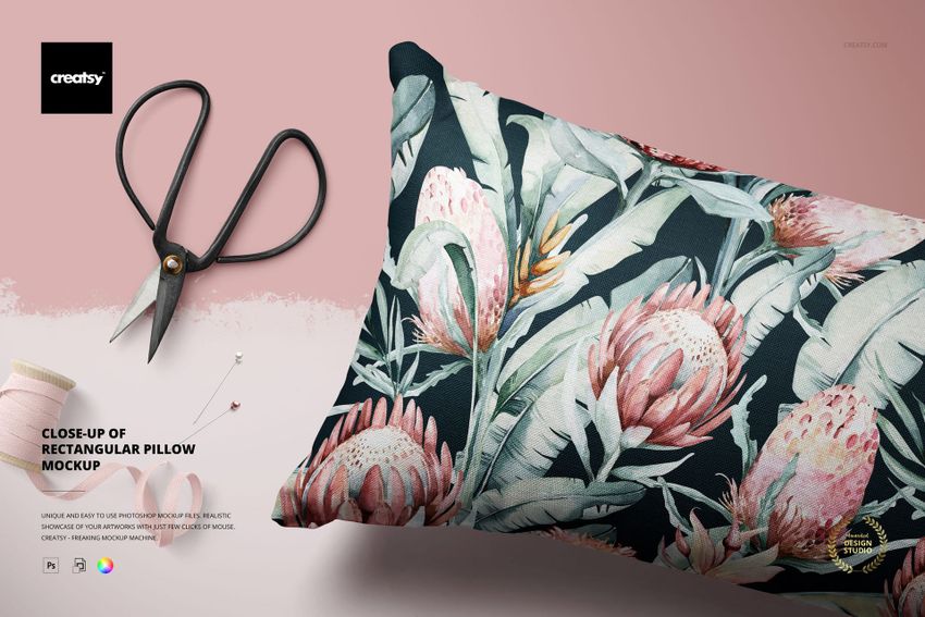 Rectangular pillow mockup featuring a dark floral design, shown from a close angle with sewing props nearby.