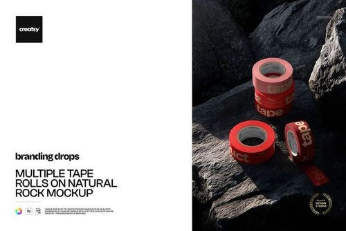 PSD mockup showing several red tape rolls with white writing resting on textured natural rocks in daylight.