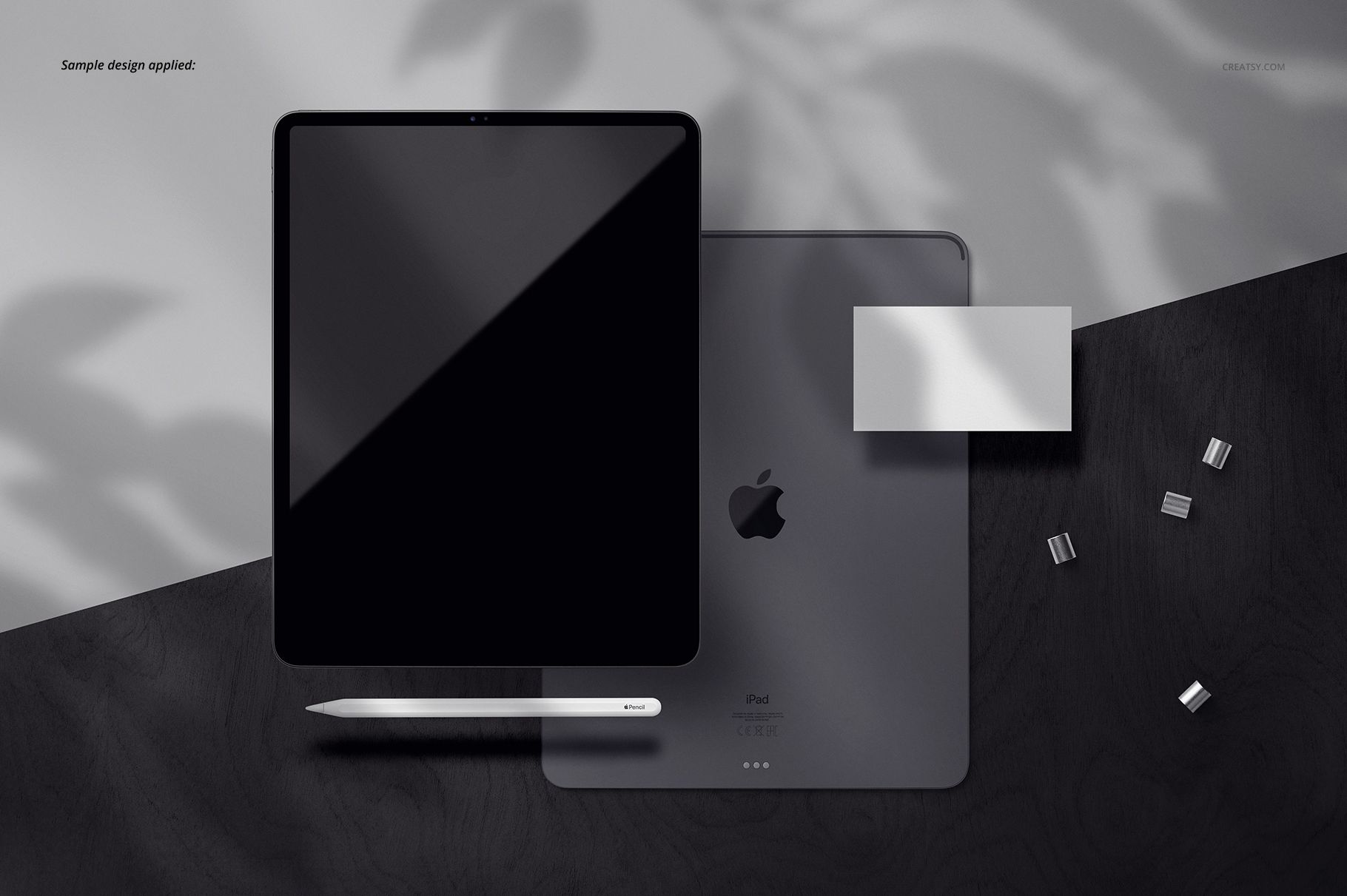 Top view of an iPad Pro mockup set with tablet, stylus, and accessories on a dark wooden surface with shadows.