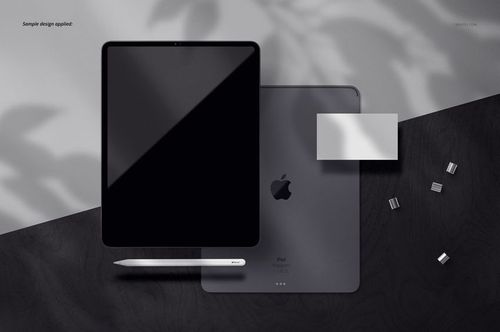 Top view of an iPad Pro mockup set with tablet, stylus, and accessories on a dark wooden surface with shadows.
