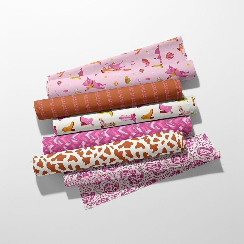 Six fabric rolls mockup arranged diagonally on a light surface, featuring pink, brown, and white patterns with western motifs.