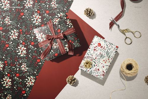 Wrapping paper mockup featuring two gift boxes with floral and berry patterns, seen from a top view with props.