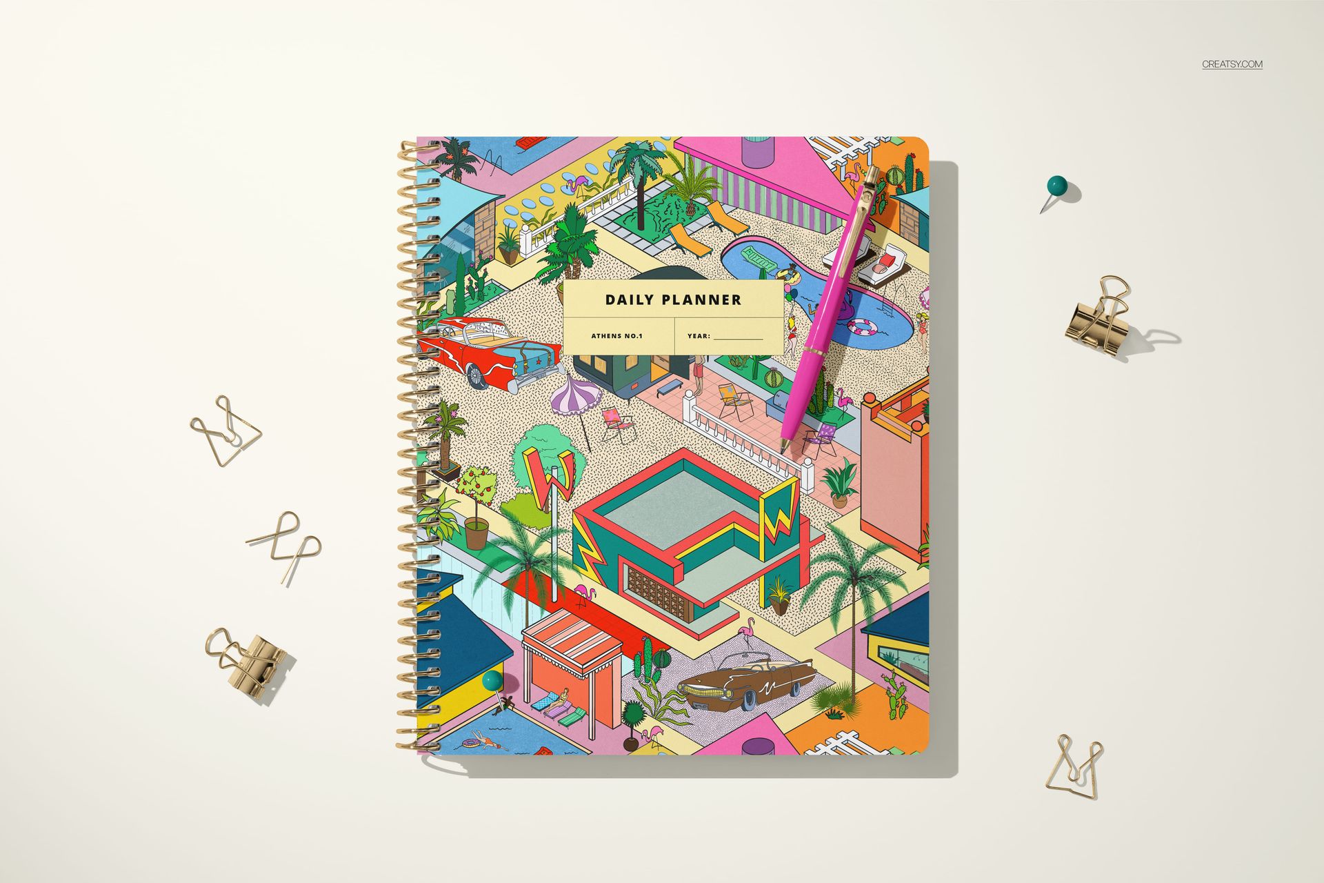 Square-shaped planner mockup with vibrant cityscape artwork on the cover, gold spiral binding, and a pen attached.