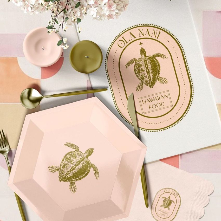 Party supplies mockup featuring a pink plate, napkin, and menu with gold turtle illustrations on a pastel geometric surface.