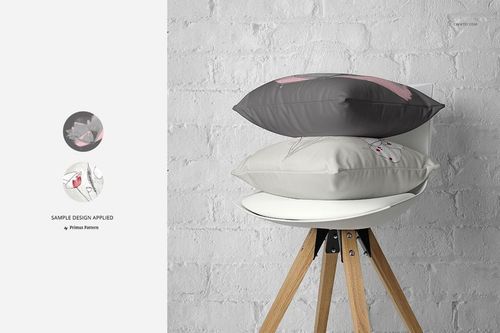 Fabric Factory pillow PSD mockup showing two patterned cushions on a white chair with wooden legs and brick background.