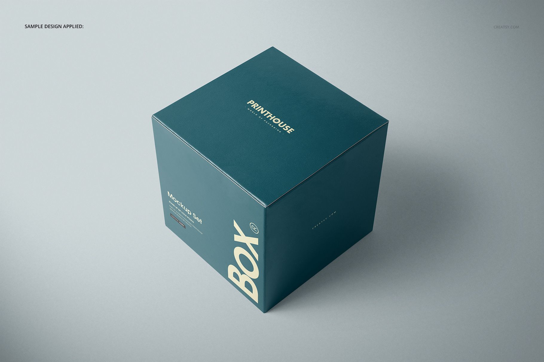 Glossy square gift box mockup in dark teal color with white text, shown from an angled top front perspective on a light background.