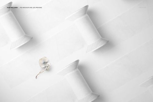 PSD mockup showing white silk ribbons on wooden spools, arranged in a neat diagonal pattern on a pale background.