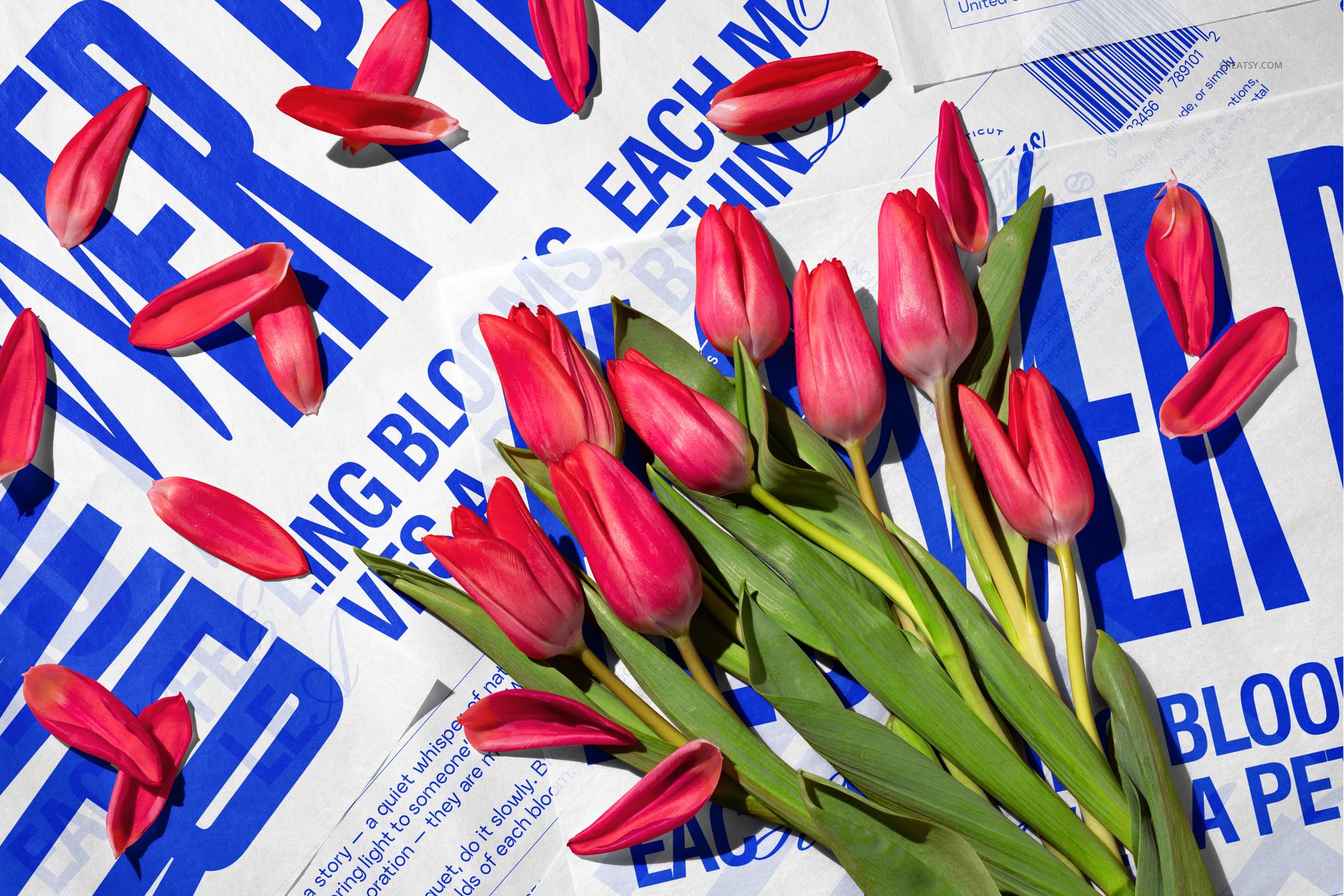 PSD mockup showing a bundle of tulips on white wrapping paper with prominent blue typography, flat lay scene.