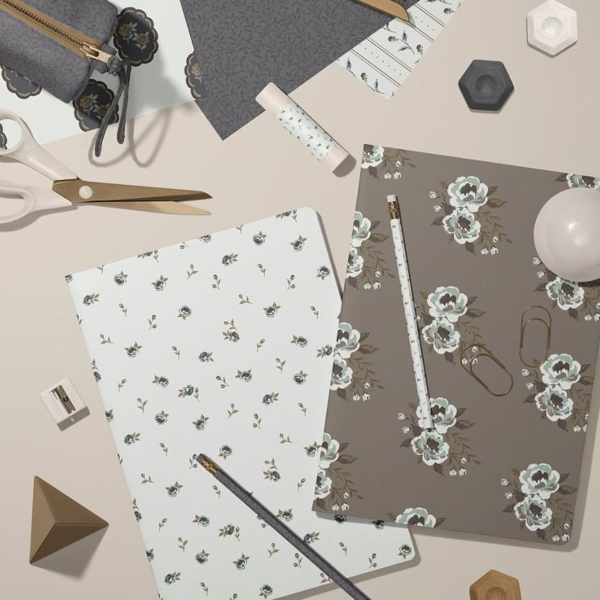 Stationery mockup featuring two classic A4 notebooks with floral covers, surrounded by office supplies on a beige surface.