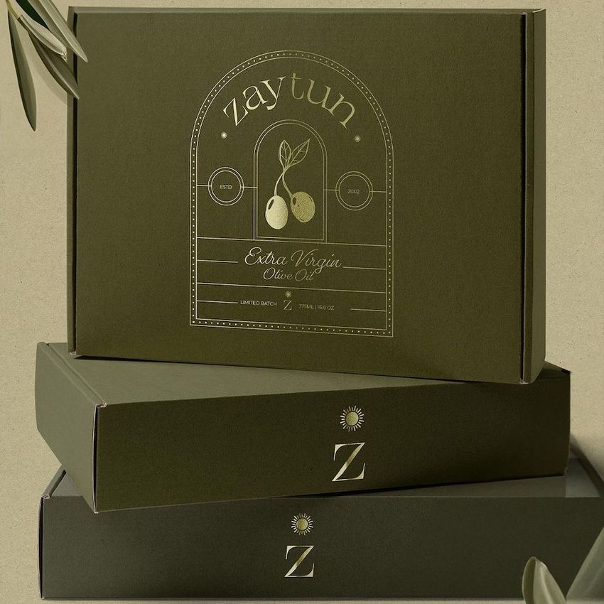 Olive green mailing box mockup with gold printed design featuring olives and text, stacked with two similar boxes on a neutral background.