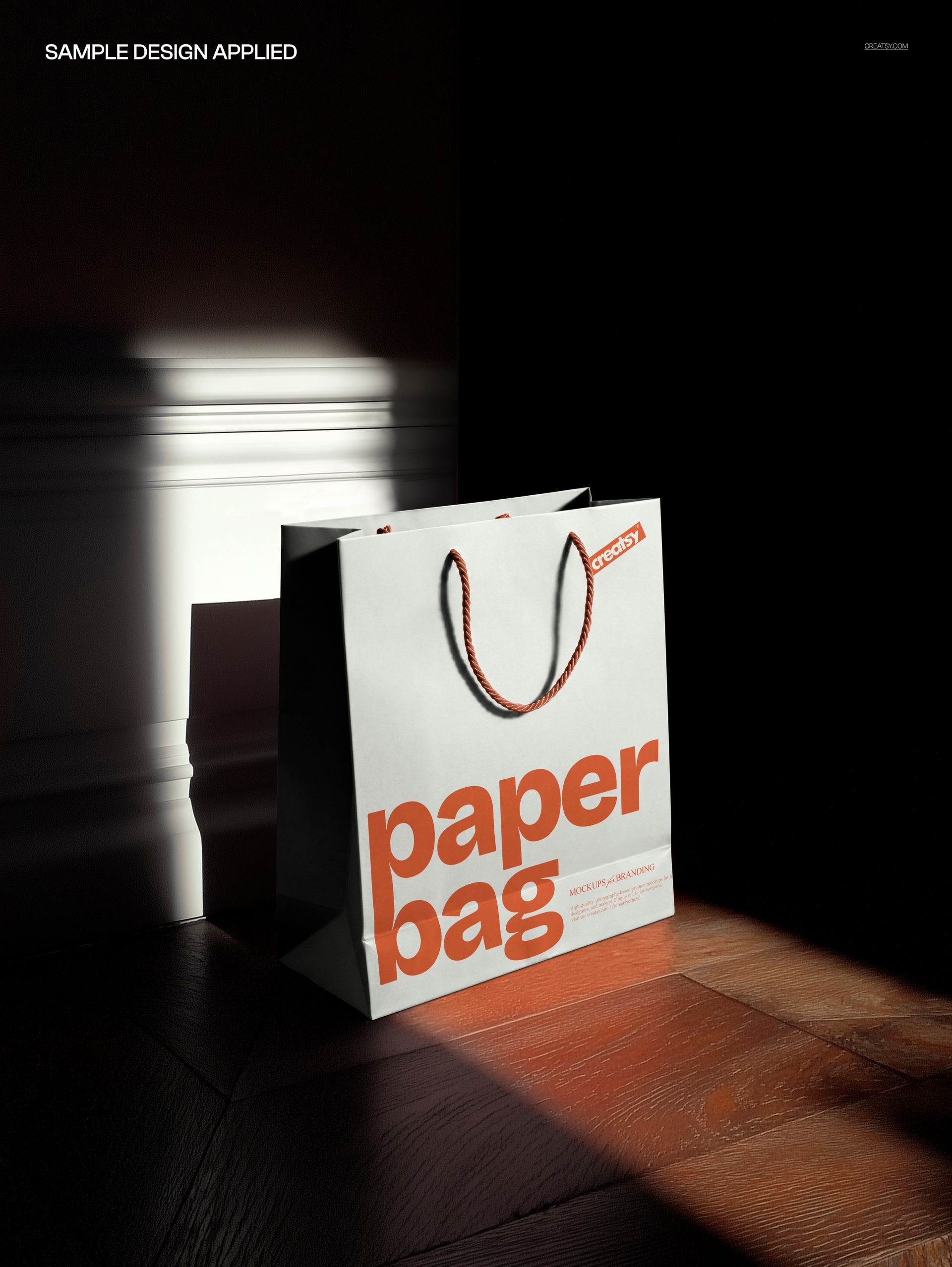 PSD mockup showing a paper shopping bag with large orange text, positioned in sunlight near a door on parquet flooring.