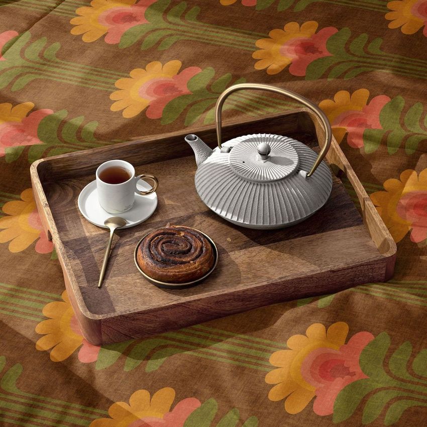 Microfiber comforter mockup with a retro floral pattern, featuring a wooden tray holding a teapot, teacup, and pastry.