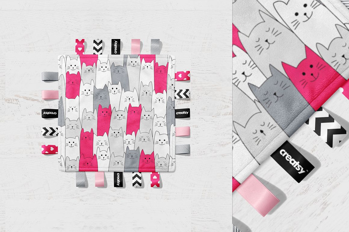 Taggie blanket mockup featuring a square blanket with pink, gray, and white cat pattern and assorted fabric tags.