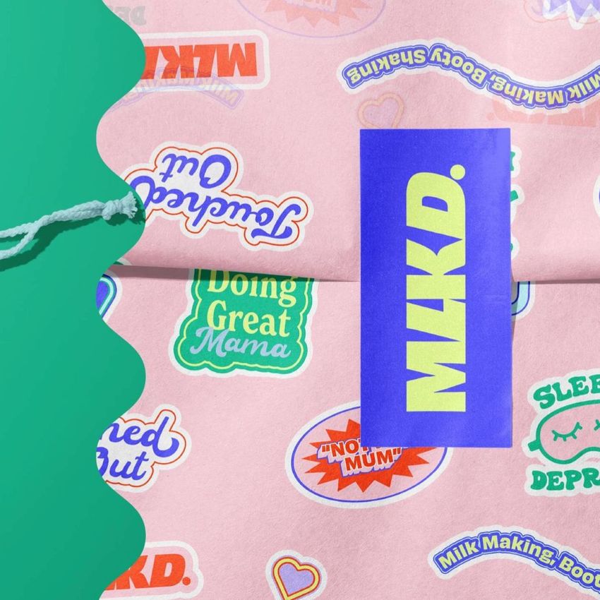 Wrapping paper mockup featuring colorful sticker designs and a bold blue sticker with yellow text, shown on a pink background.