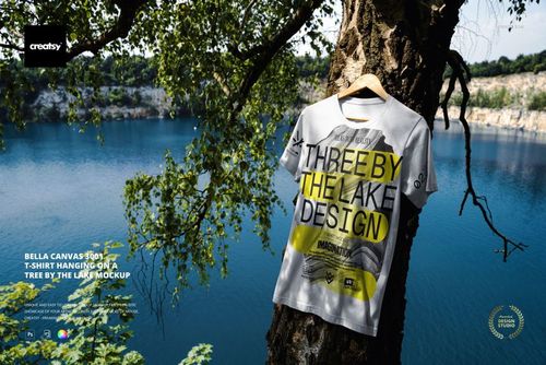 Front view of a Bella Canvas 3001 t-shirt mockup displayed on a tree by a lake, surrounded by leafy branches.