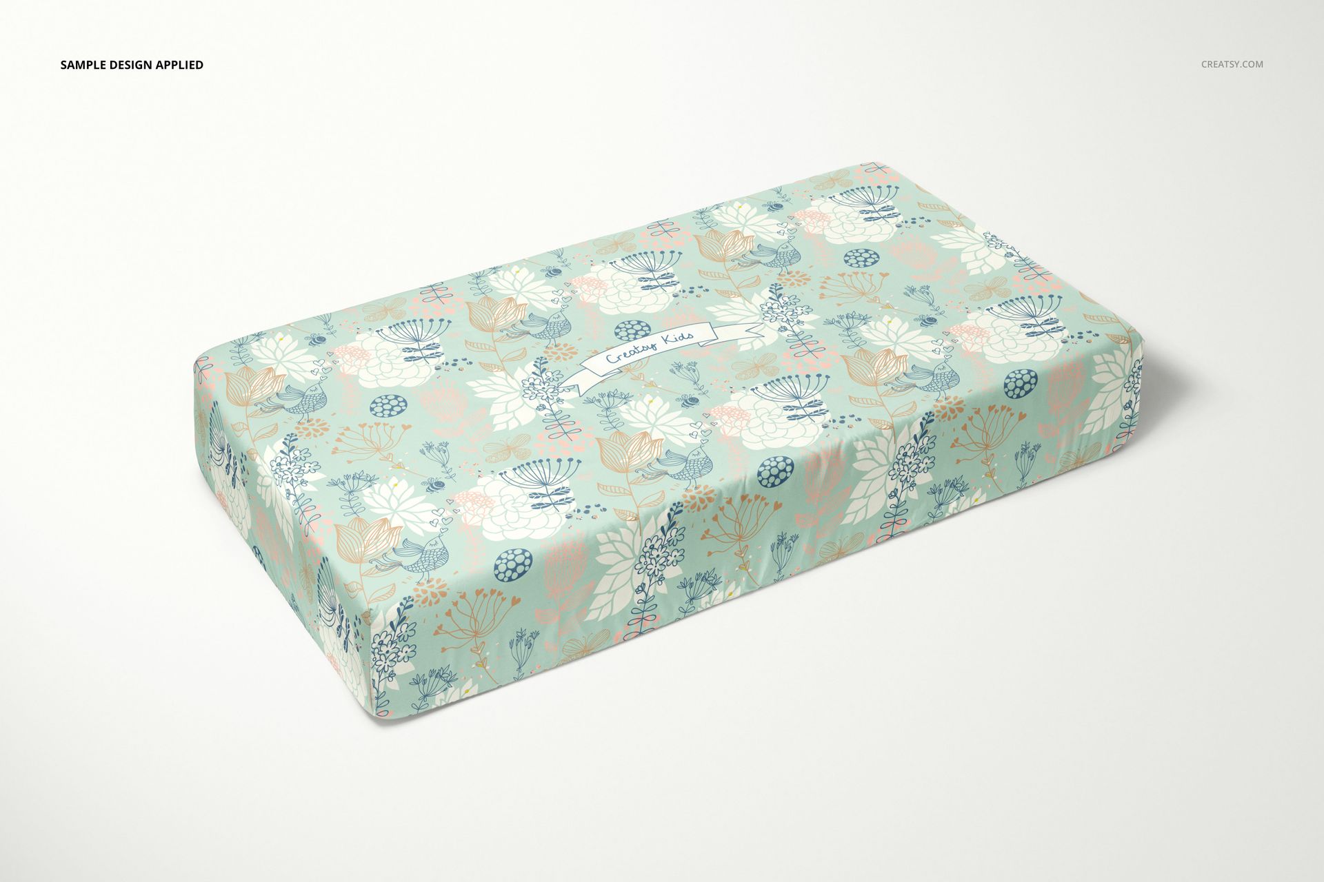 Crib sheet mockup featuring a rectangular sheet with pastel floral patterns on a light background, angled view.