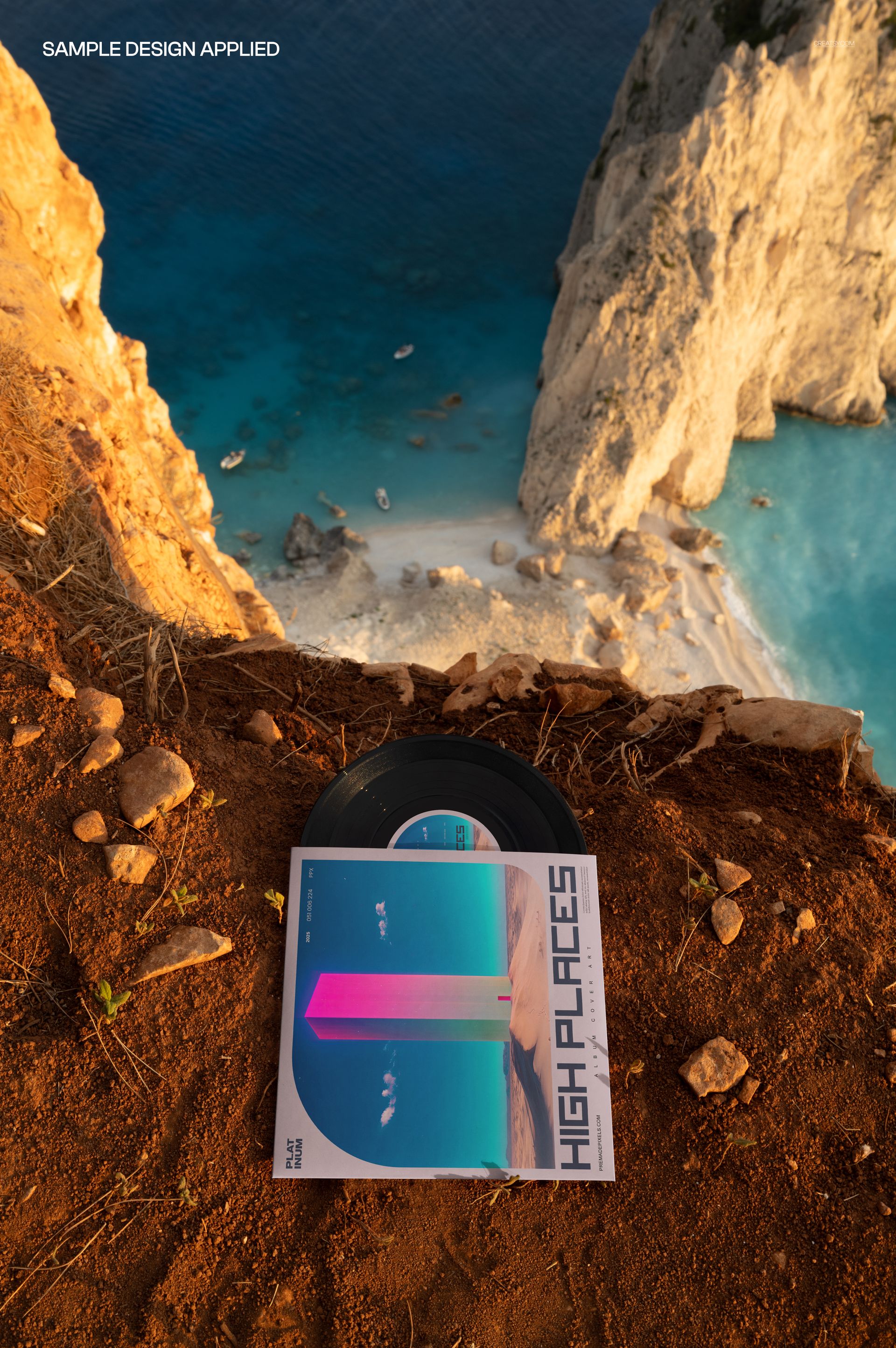 Top view of a 7 inch vinyl record and cover mockup set on reddish cliff soil above a blue coastal scene.