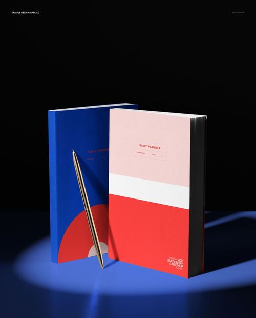 PSD mockup featuring two vertical planners in a circular pool of light, metallic pen, and dark studio setting.