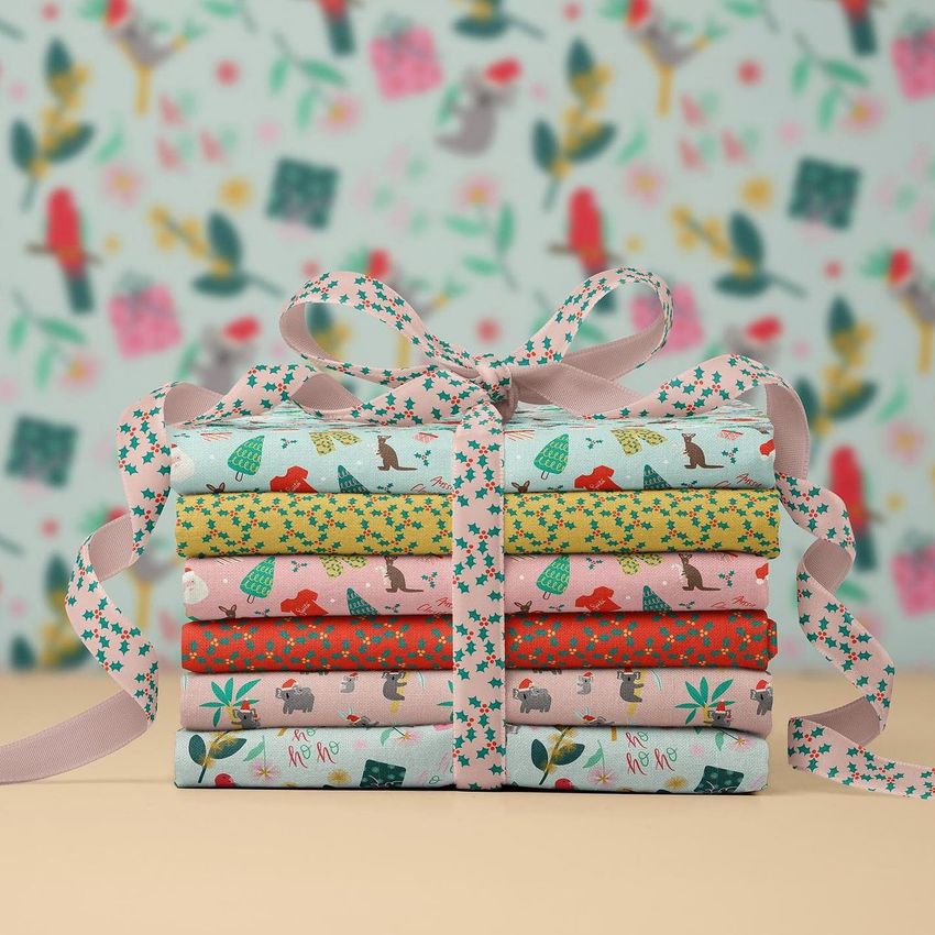 Fabric stack mockup featuring neatly folded Christmas-themed fabrics tied with a patterned ribbon, set against a festive background.