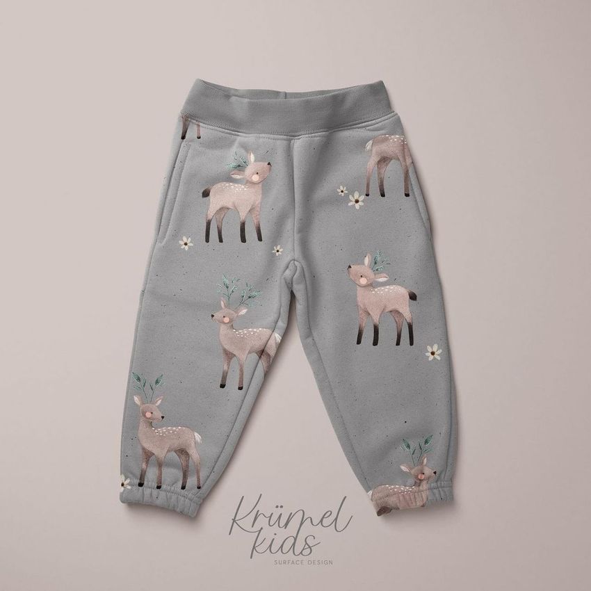 Kids fleece joggers mockup featuring a gray pair of pants with illustrated deer and leaf antler patterns on a light background.