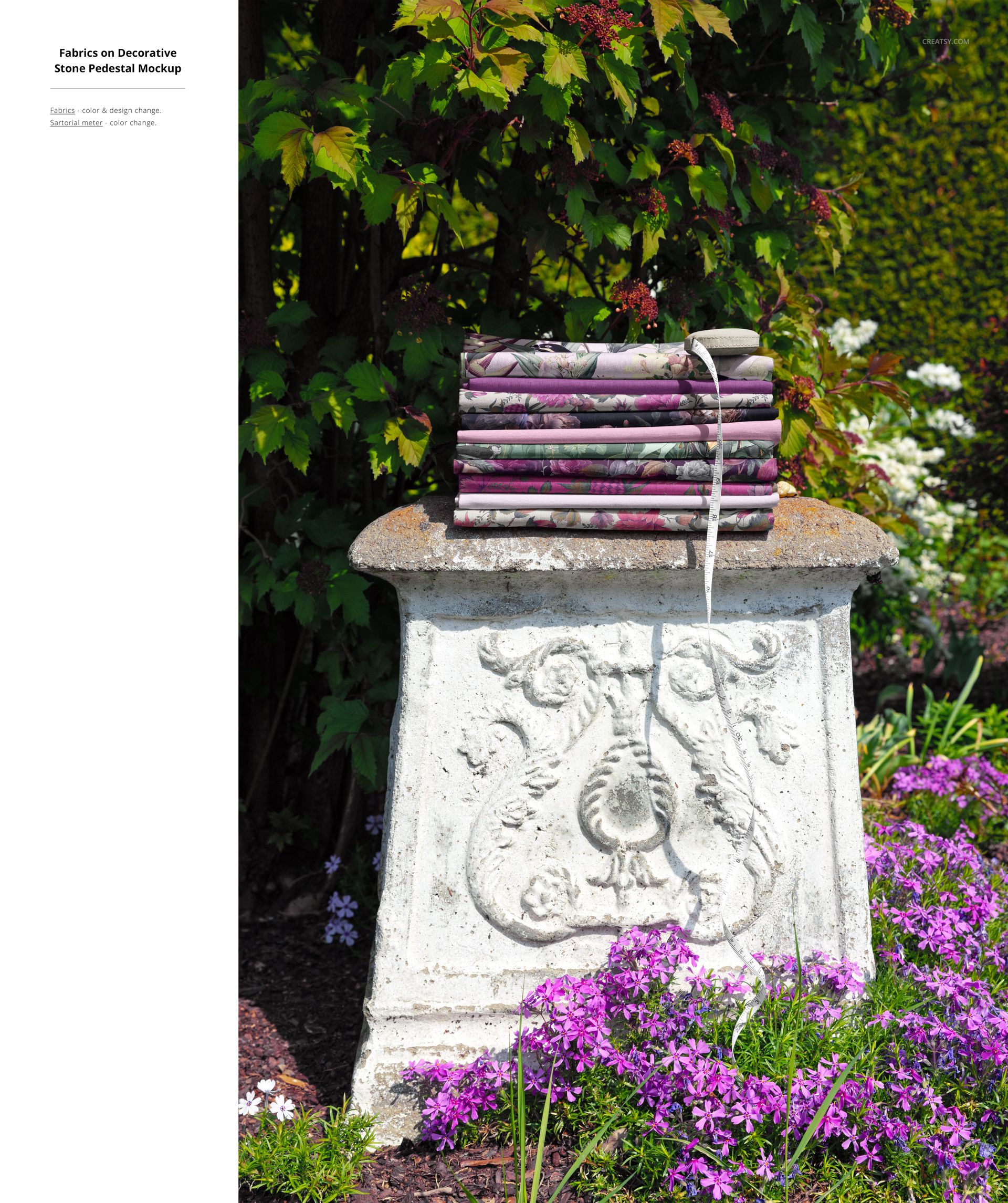 PSD mockup showing multiple fabric bolts with various designs placed on a textured pedestal among blooming flowers.