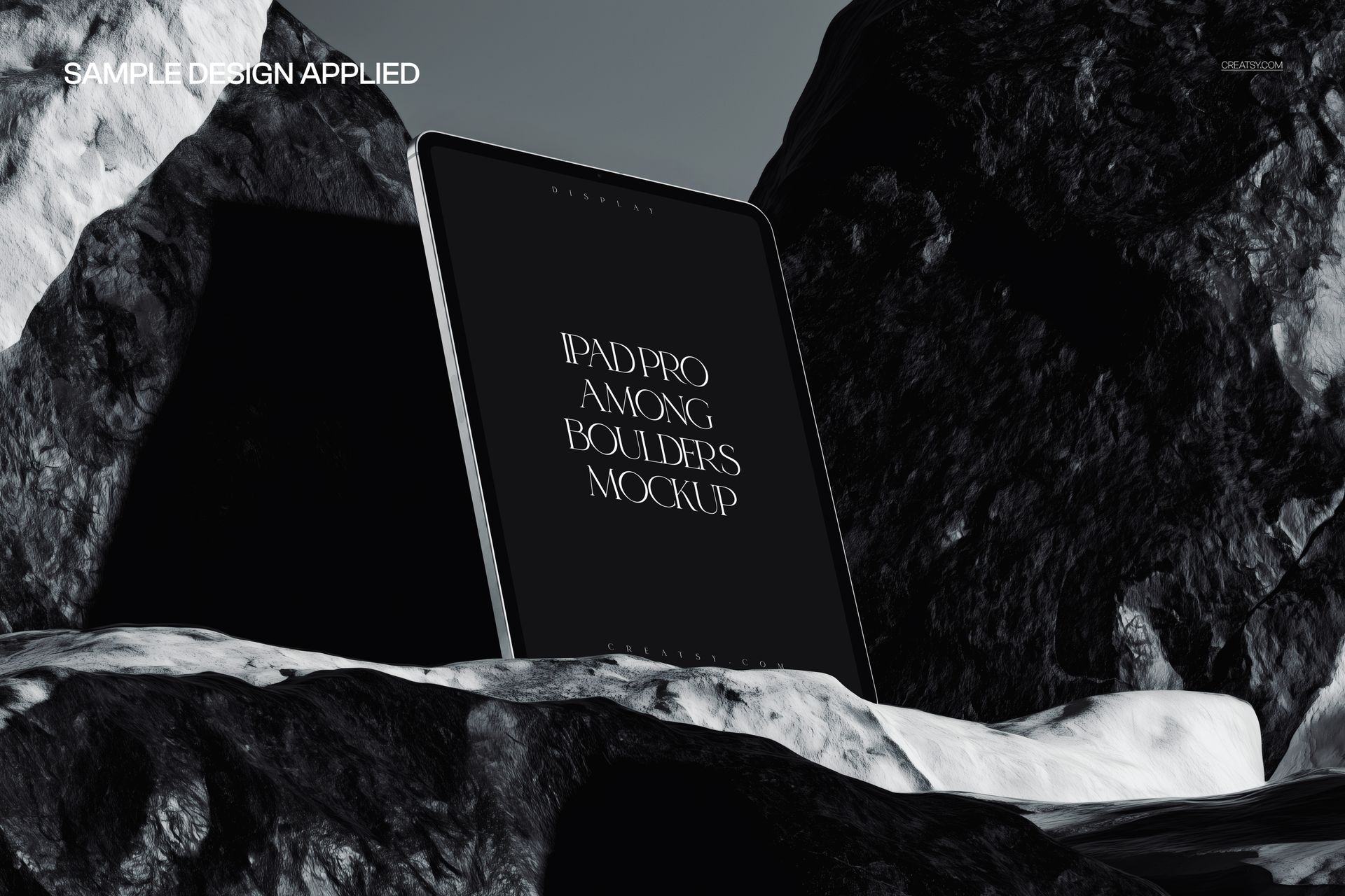 Front view of an iPad Pro mockup positioned between black and white rocks, screen facing forward in natural light.