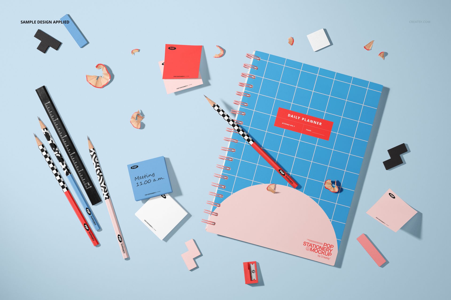Stationery mockup featuring a spiral planner, patterned pencils, sticky notes, and scattered desk items from above.