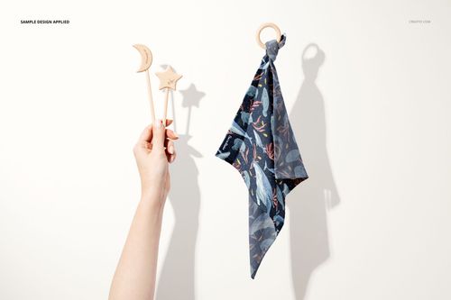 Muslin cloth wooden teether mockup set featuring a patterned muslin cloth hanging from a wooden ring and three wooden stick teethers held by a hand, shown on a light background.