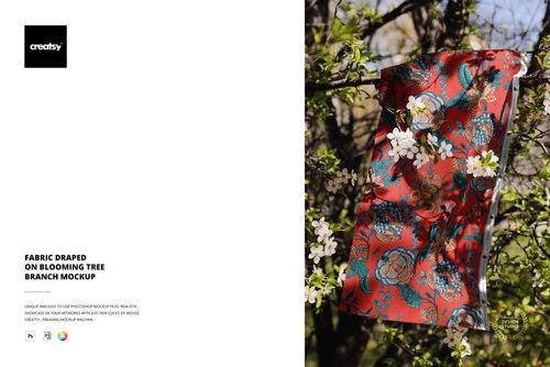 PSD mockup showing a vibrant fabric with floral design displayed on a blooming tree branch in a natural garden setting.