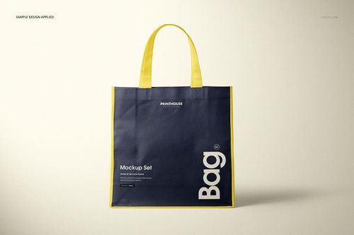 Front view of a non-woven tote bag mockup with navy blue body, yellow handles and trim, displayed on a neutral background.
