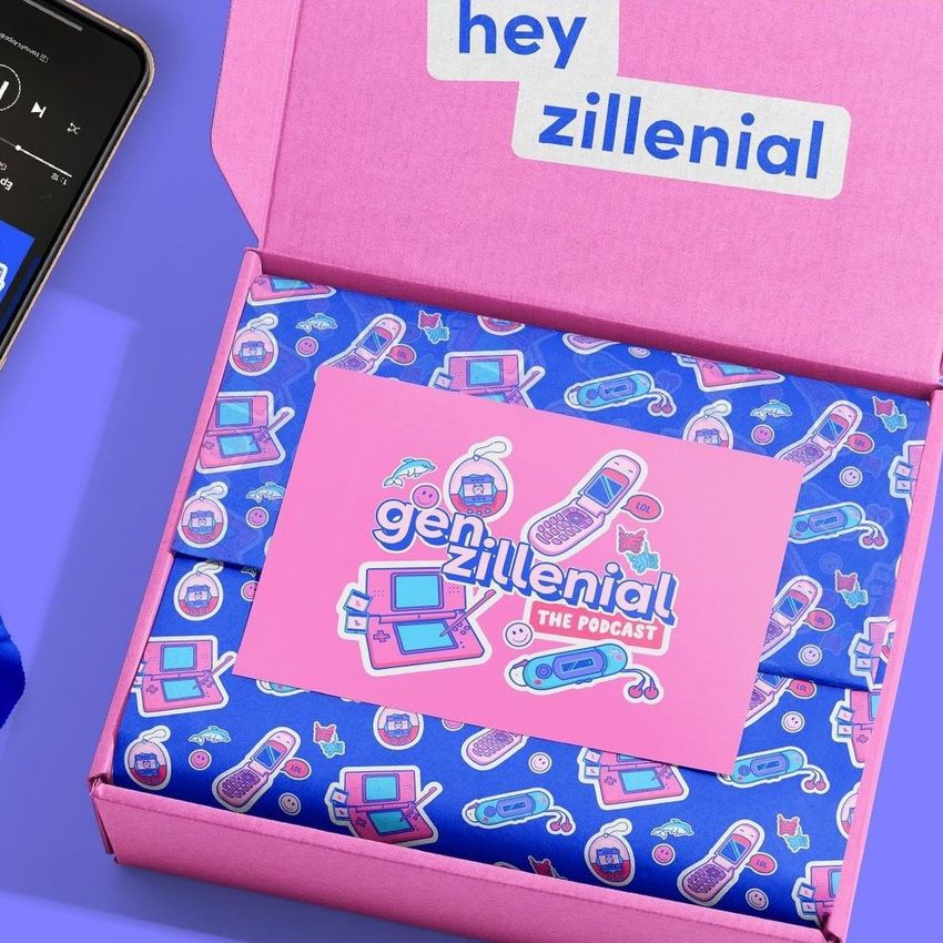 Stationery mockup featuring a pink box with 'hey zillenial' text, blue patterned wrapping paper, and a colorful card inside.