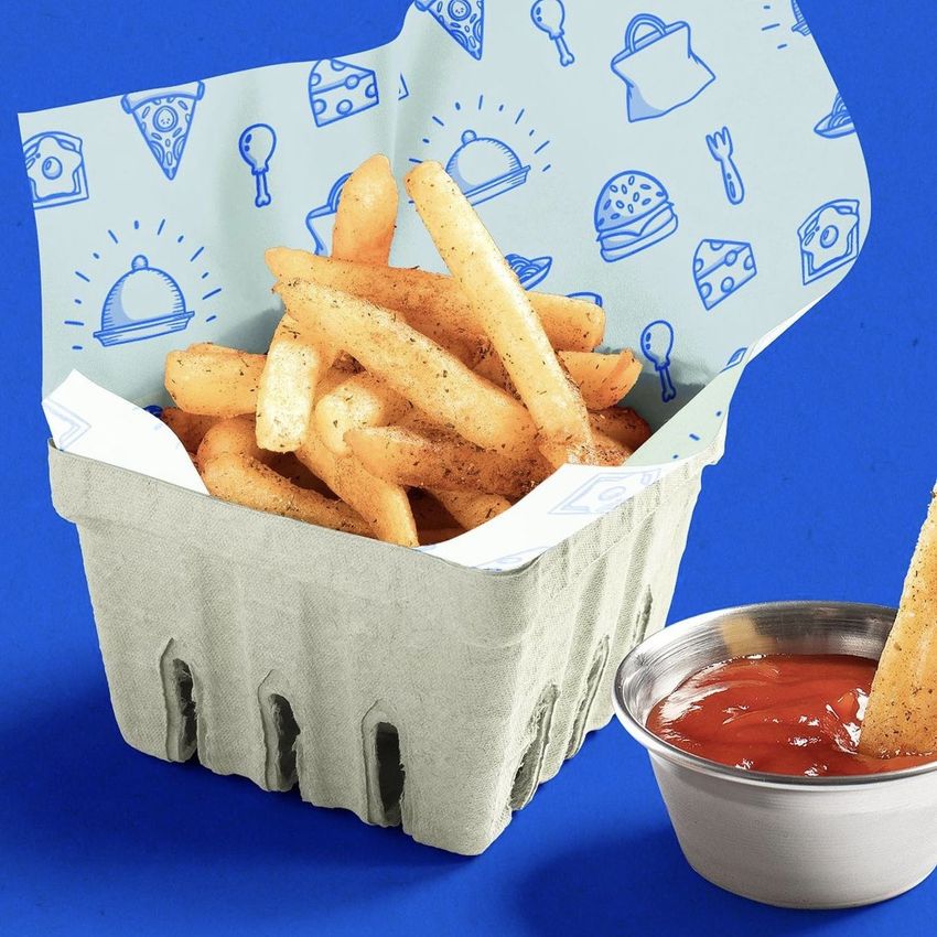 French fries served in a gray paper basket lined with food safe paper mockup featuring blue food-themed illustrations on a blue background.