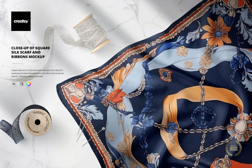 Square silk scarf mockup featuring intricate blue, orange, and cream patterns, shown with decorative ribbons and spools.