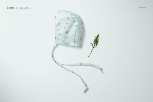 Baby bonnet mockup featuring a soft blue fabric with delicate pink flowers, displayed flat beside a sprig on white background.