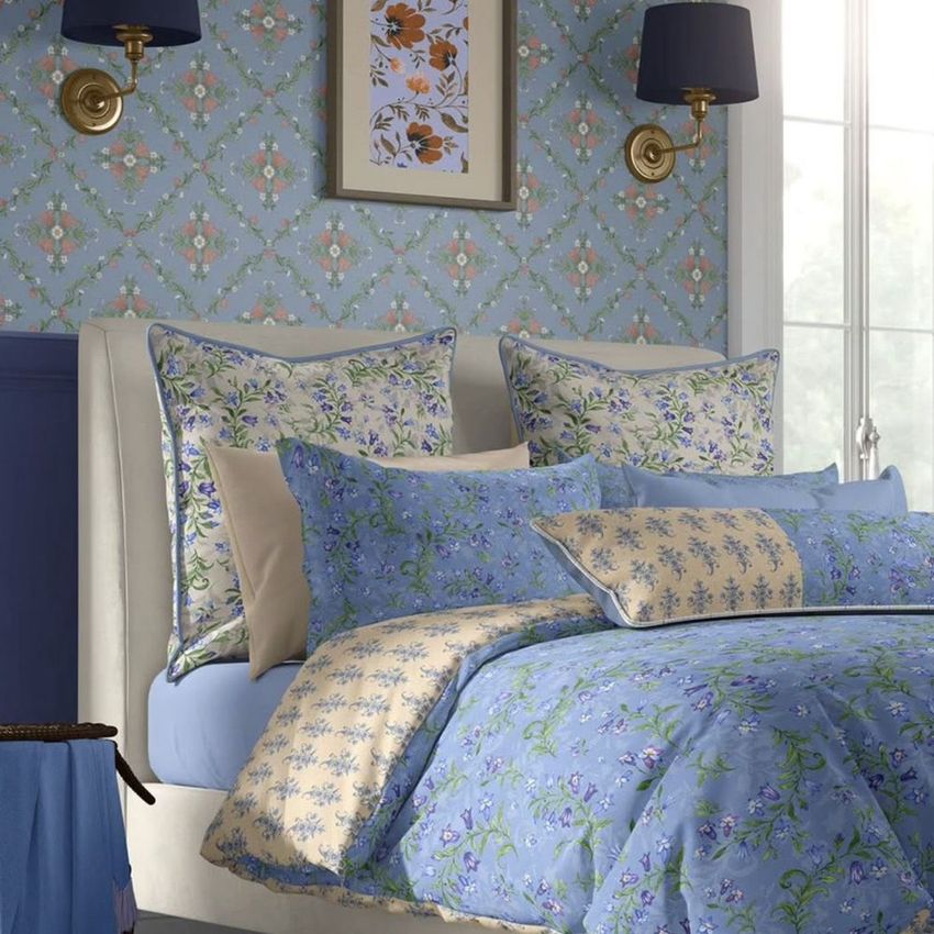 Cottage style bedroom bedding mockup featuring a bed with blue and beige floral-patterned linens, pillows, and wallpaper.