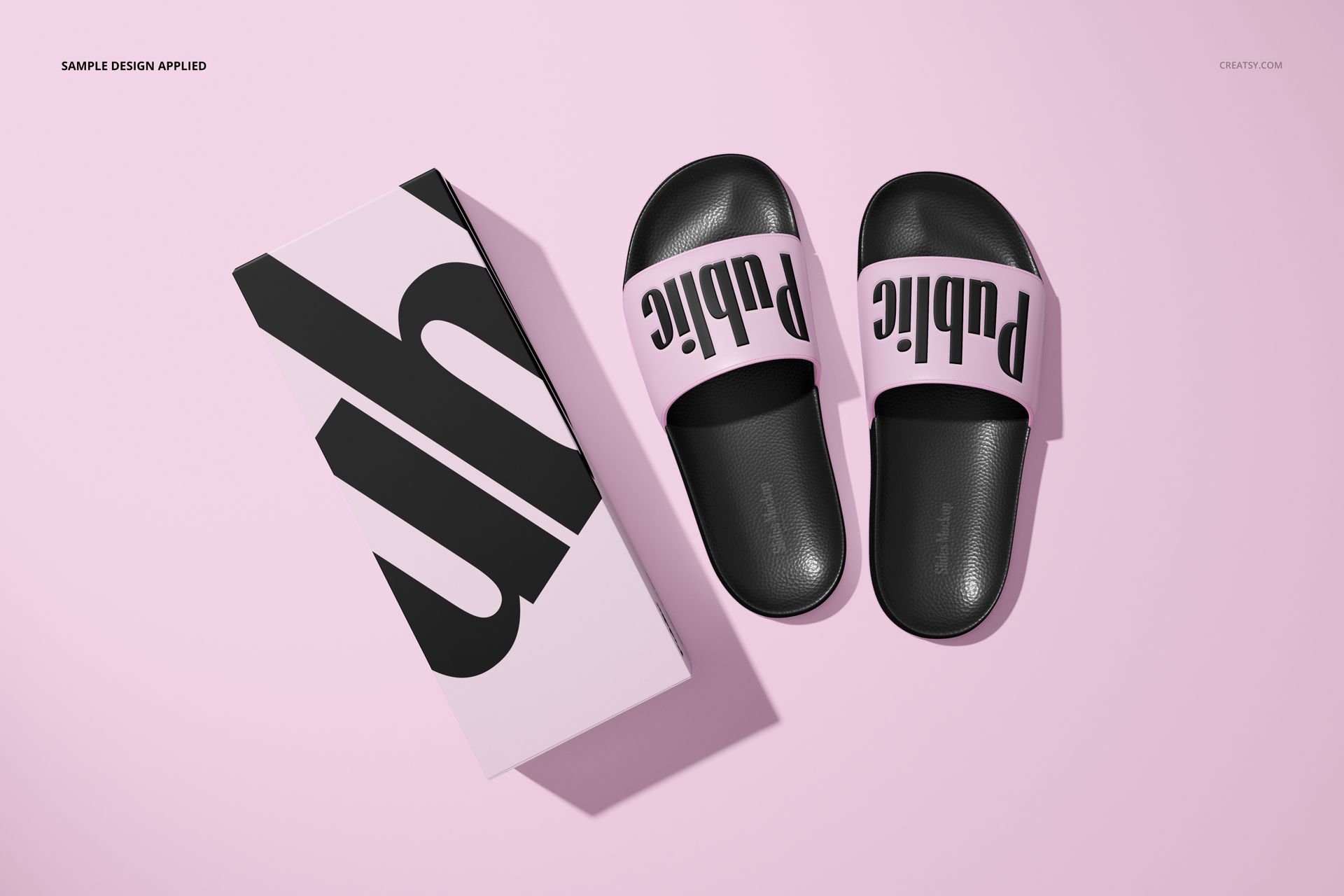 PSD mockup of slide sandals in black and light pink, displayed alongside a patterned box on a pastel pink background.