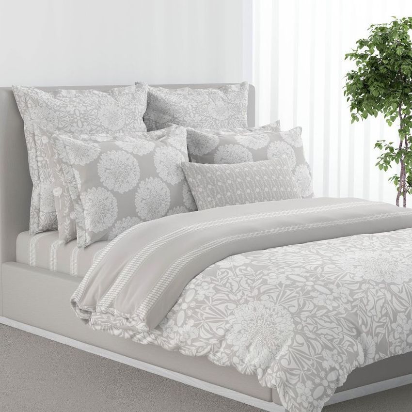 Bedroom scene bedding mockup featuring a neatly made bed with light gray and white floral patterned duvet and pillows.